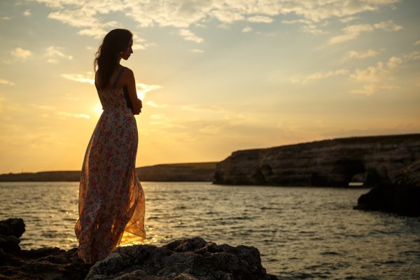Девушка на фоне моря в длинном платье