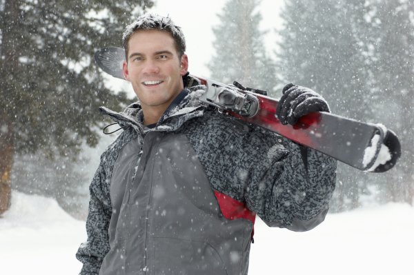 Мужчина на лыжах в лесу зимой