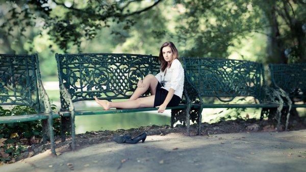 Девушка сидит на скамейке в парке
