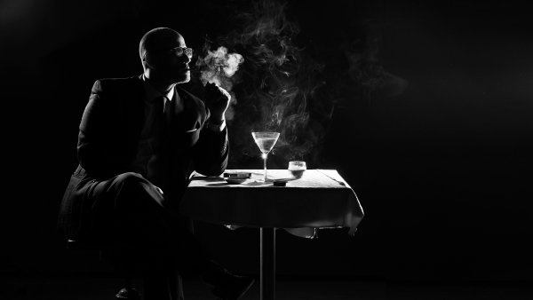 Мужчина курит за столиком в кафе