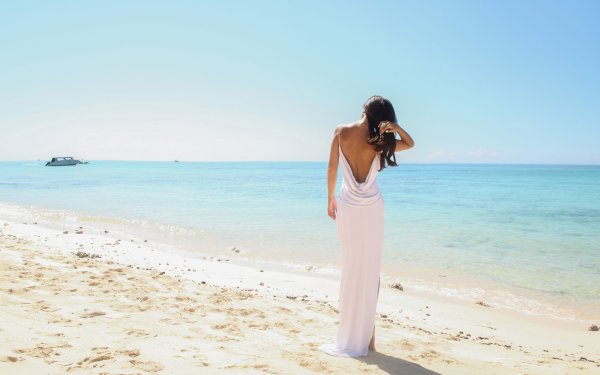 Девушка в белом платье со спины у моря