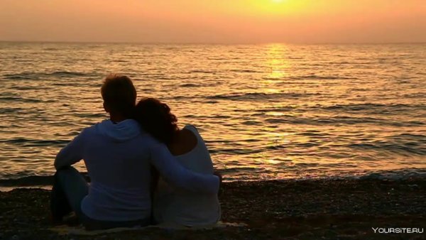 Пара сидит на берегу моря